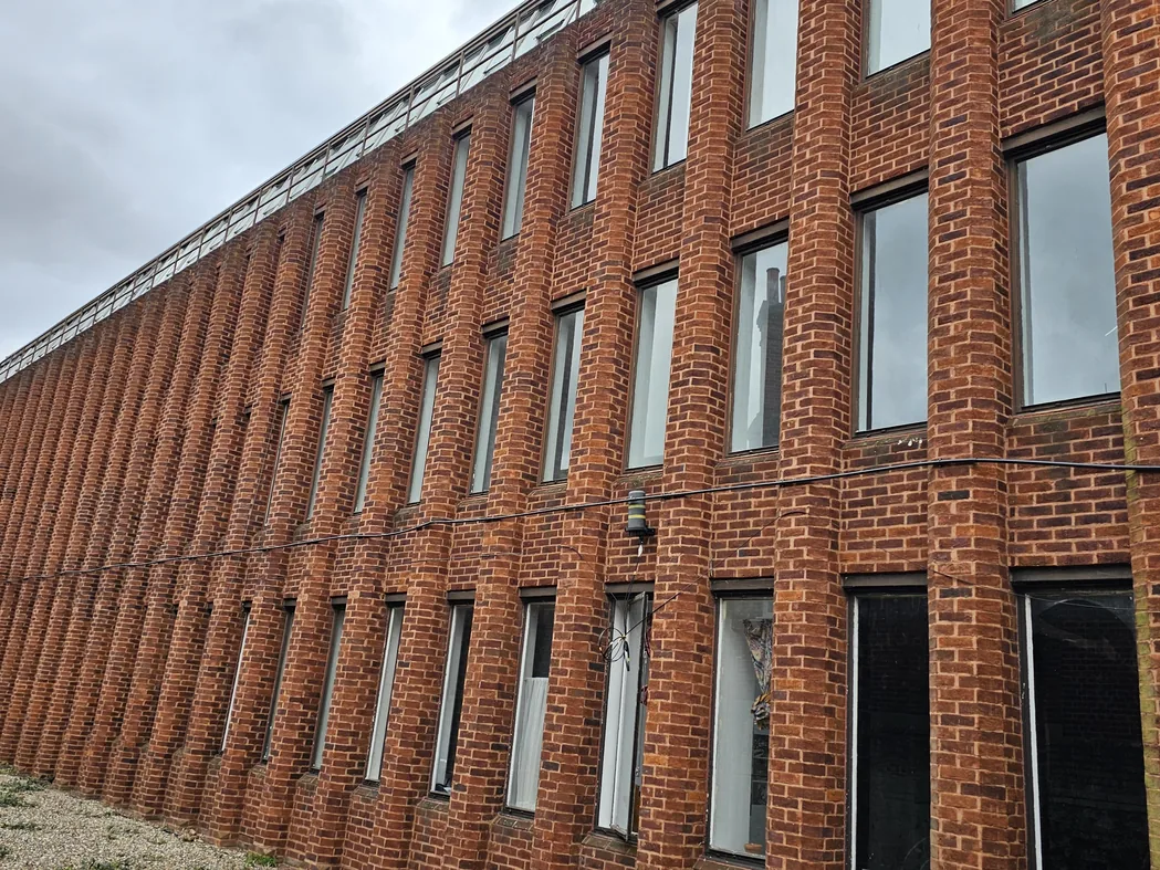 Long red-brick office elevation with vertical pier detailing and ribbon windows